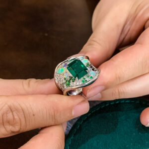 A bespoke piece: showcasing a majestic emerald adorned with opals, diamonds, and sapphires.