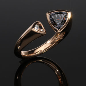 A sophisticated bespoke geometric ring with trillion cut grey spinel and white sapphire.