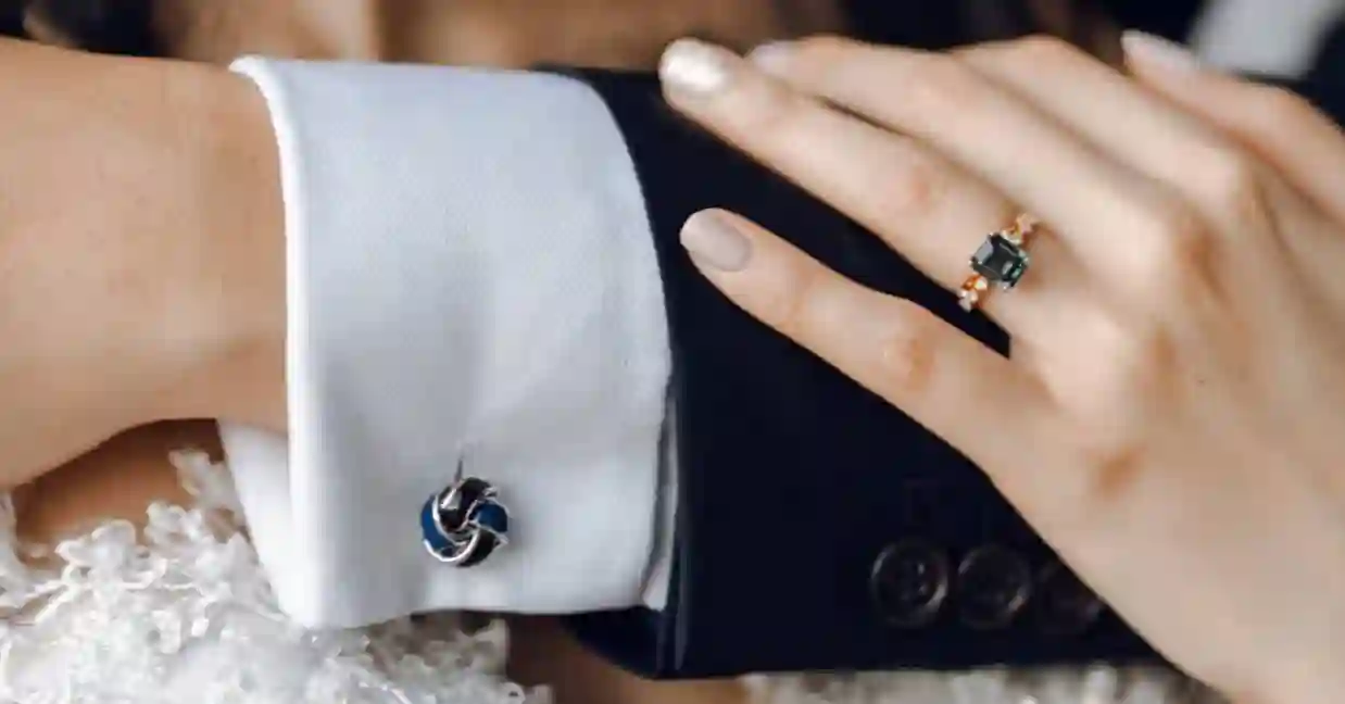 Close-up of bride wearing gemstone ring while holding groom’s arm, symbolising customised wedding ring designs popular in Singapore.