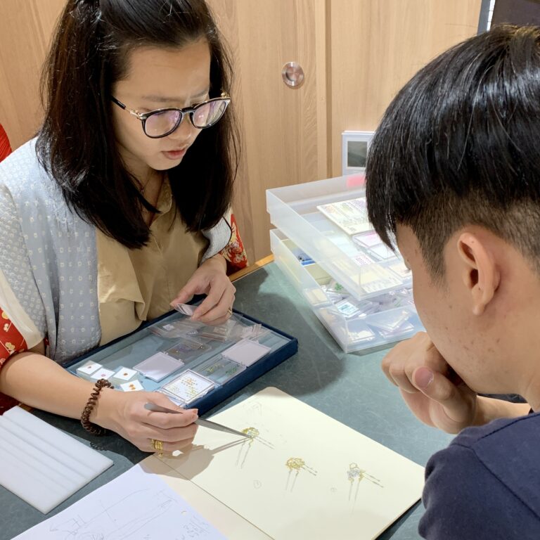 Jewellery consultant discussing gemstone ring design with customer, showcasing gemstone jewellery selection in Singapore boutique showroom.
