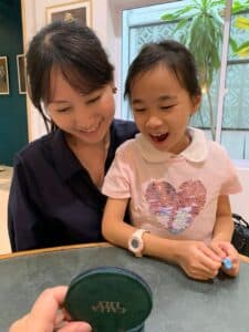 Mother and daughter sharing a joyful moment while admiring bespoke jewellery in Singapore inspired by motherhood memories and meaningful design.