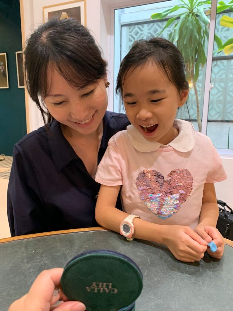 Mother and daughter sharing a joyful moment while admiring bespoke jewellery in Singapore inspired by motherhood memories and meaningful design.